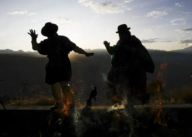 Aymaras hold up their hands to receive the first rays of sunlight during a New Year's ritual in El Alto, Bolivia, Tuesday, June 21, 2022. Aymara Indigenous communities are celebrating the 5,530th Andean New Year referred to as “Willka Kuti” or return of the sun in Aymara, coinciding with the southern hemisphere's June 21 winter solstice. (Photo by Juan Karita/AP Photo)