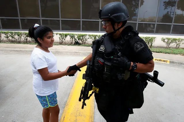 A child shakes hands with a SWAT officer as she pays respects at a makeshift memorial at Dallas Police Headquarters following the multiple police shootings in Dallas, Texas, U.S., July 9, 2016. (Photo by Carlo Allegri/Reuters)