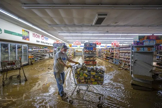 Dale Blair, an employee at Isom IGA in Isom, Ky., pushes a cart full of canned goods to be thrown out, Monday, August 1, 2022. Historic floods last week ravaged the store, spoiling its inventory. (Photo by Ryan C. Hermens/Lexington Herald-Leader via AP Photo)