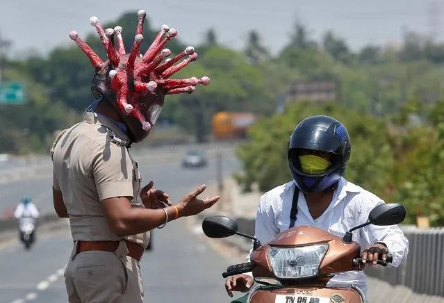 Rajesh Babu, a police officer, wearing a helmet depicting coronavirus, requests a commuter to stay at home during a 21-day nationwide lockdown to limit the spreading of coronavirus disease (COVID-19), in Chennai, India, March 28, 2020. (Photo by P. Ravikumar/Reuters)