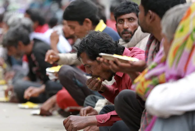 Homeless and impoverished Indians eat a meal distributed by the Delhi government in New Delhi, India, Thursday, March 26, 2020. (Photo by AP Photo/Stringer)