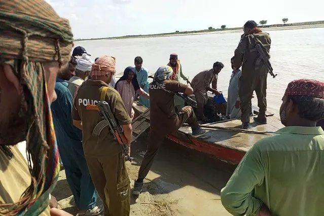 Policemen and local villagers prepare to search for the victims drowned at Indus River after an overcrowded boat carrying a Pakistan wedding party capsized on the outskirt of Sadiqabad town on July 18, 2022. At least 18 women drowned and dozens more people are missing after an overcrowded boat carrying a Pakistan wedding party capsized on July 18, officials said. (Photo by AFP) (Photo by /AFP Photo via Getty Images)