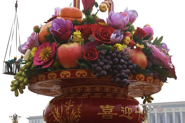 Workers stand on a platform put finishing touch on a giant basket decorated with replicas of flowers and fruits on display at Tiananmen Square in Beijing, Monday, September 25, 2017. Hundreds of thousands foreign and domestic tourists are expected to flock to the square to celebrate the National Day and Mid-Autumn Festival over the week-long holidays starting on Sept. 30. (Photo by Andy Wong/AP Photo)