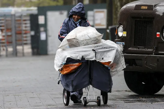 A United States Postal Service (USPS) mail carrier pushes her cart while delivering mail in the rain on Manhattan's Upper West Side during the outbreak of the coronavirus disease (COVID-19) in New York City, New York, U.S., April 13, 2020. (Photo by Mike Segar/Reuters)