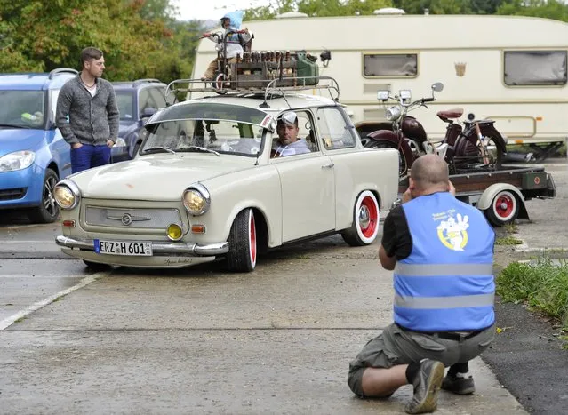 A jury member takes a photo of a tuned Trabant 601 car as fans of the East German Trabant car gather for their 7th annual get-together on August 23, 2014 in Zwickau, Germany. Hundreds of Trabant enthusiasts arrived to spend the weekend admiring each others cars, trading stories and enjoying activities. The Trabant, dinky and small by modern standards, was the iconic car produced in former communist East Germany and today has a strong cult following. (Photo by Matthias Rietschel/Getty Images)