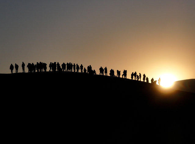 Tourists watch the sunrise in the desert at the Mingsha Mountain and Crescent Spring scenic spot on New Year's Day on January 1, 2025 in Dunhuang, Jiuquan City, Gansu Province of China. (Photo by Zhang Xiaoliang/VCG via Getty Images)