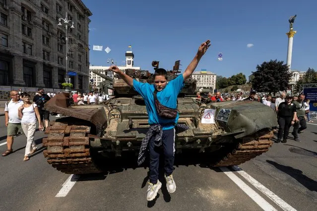 A boy jumps from a tank at an exhibition of destroyed Russian military vehicles and weapons, dedicated to the upcoming country's Independence Day, amid Russia's attack on Ukraine, in the centre of Kyiv, Ukraine on August 21, 2022. (Photo by Valentyn Ogirenko/Reuters)