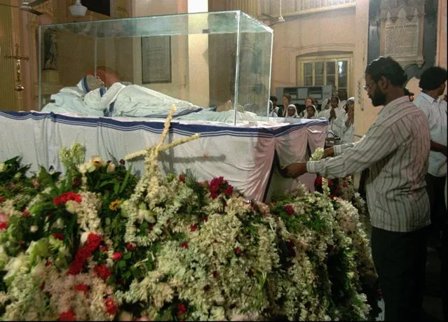 A mourner places a garland of flowers on the body of Mother Teresa, at a church in Calcutta Sunday, September 7, 1997. The funeral of the “sister of mercy” will be held on Saturday. (Photo by Sherwin Crasto/AP Photo)