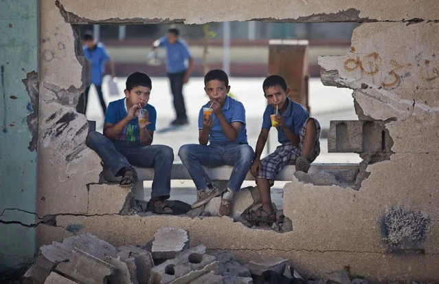 Palestinian school boys drink iced juice as they sit on a damaged wall of a school in Gaza City's Shijaiyah neighborhood, Sunday, September 14, 2014. Some half million Gaza children made a delayed return to school on Sunday after a devastating 50-day war with Israel that killed more than 2,100 Palestinians and damaged hundreds of school buildings. (Photo by Khalil Hamra/AP Photo)