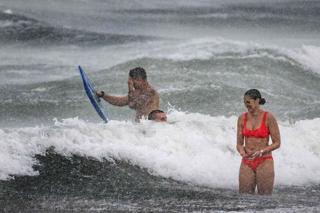 People play in the surf through the rain on Cocoa Beach on September 28, 2022, as the eastern coast of central Florida braces for Hurricane Ian. Heavy winds and rain pummelled Florida on Wednesday as Hurricane Ian intensified to just shy of the strongest Category 5 level, threatening to wreak “catastrophic” destruction on the southern US state. Forecasters warned of a looming once-in-a-generation calamity, with life-threatening storm surges, extensive flooding and devastating winds promising what Florida Governor Ron DeSantis called a "nasty" natural disaster. (Photo by Jim Watson/AFP Photo)