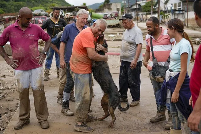 A man reunites with his dog, rescued by neighbors from the mud, after flooding caused by intense rains in Las Tejerias, Venezuela, Sunday, October 9, 2022, after (Photo by Matias Delacroix/AP Photo)