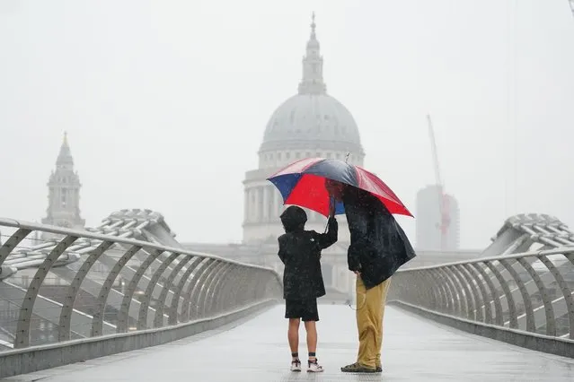 People with umbrellas walking in the rain in London on Wednesday, August 17, 2022. After weeks of sweltering weather, which has caused drought and left land parched, the Met Office's yellow thunderstorm warning forecasts torrential rain and thunderstorms that could hit parts England and Wales. (Photo by Victoria Jones/PA Images via Getty Images)