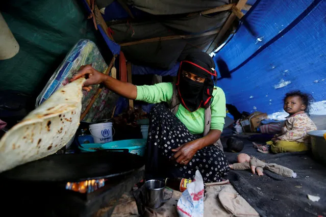 A woman makes bread inside her tent at a camp for internally displaced people near Sanaa, Yemen, May 24, 2016. (Photo by Khaled Abdullah/Reuters)