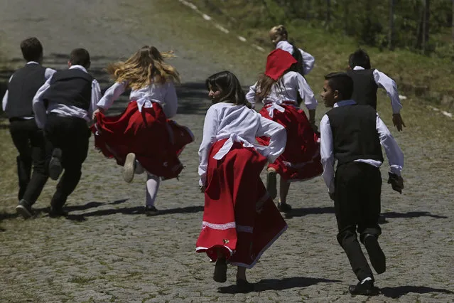 In this November 11, 2017 photo, children dressed in traditional outfits play during the Azorean Culture Festival which celebrates the culture of the Azores, the Portuguese island chain in the mid-Atlantic, in Enseada de Brito, in Brazil's Santa Catarina southern state. “We have to make sure that our culture always stays alive, not let it die”, said Andre Cordeiro, who leads one of the singing and dancing groups that performed this year. “We are able to pass it on from generation to generation”. (Photo by Eraldo Peres/AP Photo)