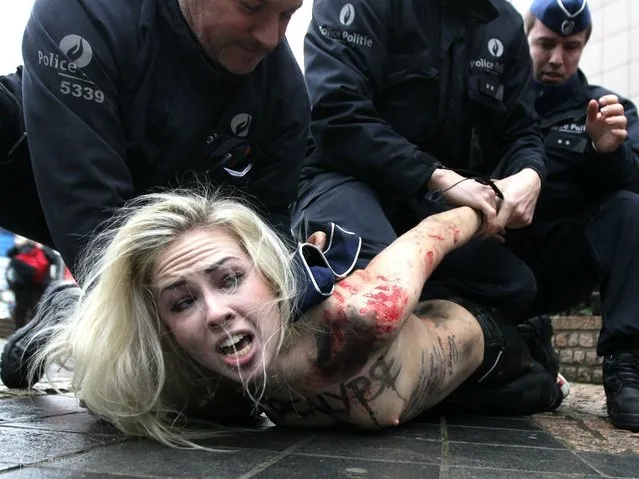 An activist of Ukraine's feminist movement Femen is taken away by the police as she demonstrates by the EU Council building where the EU-Russia summit is taking on December 21, 2012 in Brussels, Belgium. (Photo by Georges Gobet/AFP Photo)