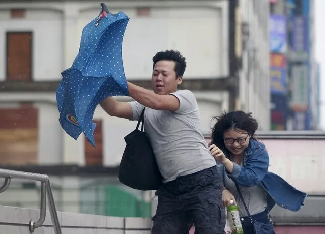 People hold onto their umbrella while walking against strong winds caused by Typhoon Dujuan in Taipei, Taiwan, September 28, 2015. (Photo by Pichi Chuang/Reuters)