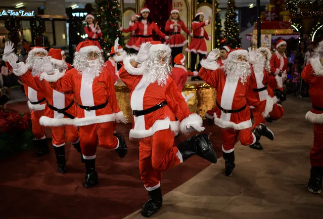 Performers clad in Santa Claus outfits dance at a shopping mall in Kuala Lumpur on December 18, 2017. Every year as Christmas approaches, shopping malls across Malaysia are decorated with beautiful light displays and offer year-end discounts to lure shoppers. (Photo by Mohd Rasfan/AFP Photo)