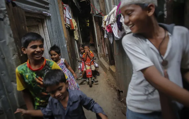 A boy rides his tricycle as others play inside a slum alley in Mumbai August 19, 2013. (Photo by Danish Siddiqui/Reuters)