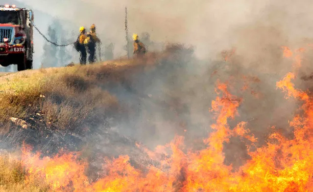 Firefighters are seen through heat from flames as they battle the Apple fire near Banning, California on August 1, 2020. 4,125 acres have burn in Cherry Valley, about 2,000 people have received evacuation orders in the afternoon of August 1. Around 8PM the fire spread to 12,000 acres. (Photo by Josh Edelson/AFP Photo)