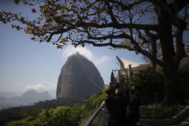 Workers take a break with Sugar Loaf mountain in the background, amid the new coronavirus pandemic in Rio de Janeiro, Brazil, Wednesday, August 12, 2020. Rio de Janeiro's iconic tourist attractions, the Aquarium, Sugarloaf Mountain, the Christ the Redeemer statue, and the “Rio Star” Ferris wheel will re-open to tourism next Saturday, as the city eases its lockdown. (Photo by Silvia Izquierdo/AP Photo)