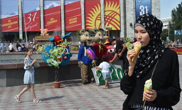 A Kyrgyz woman enjoys ice cream during the celebrations marking the 29th anniversary of Kyrgyzstan's independence from the Soviet Union at the Ala-Too Square in Bishkek on August 31, 2020. (Photo by Vyacheslav Oseledko/AFP Photo)