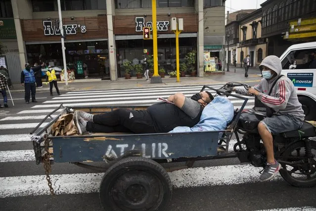 A commuter rests on the flatbed of a motorbike that will take him to work, a block away from the Congress in Lima, Peru, Friday, September 18, 2020. A high Peruvian court rejected a request by President Martín Vizcarra Thursday to halt impeachment proceedings being pushed by opposition lawmakers who contend he tried to cover up ties with a controversial ally. (Photo by Rodrigo  Abd/AP Photo)
