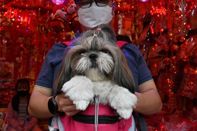 A man takes his dog as people shop for Chinese ornaments and food in Jakarta on January 8, 2023, ahead of Chinese New Year on January 22. (Photo by Adek Berry/AFP Photo)