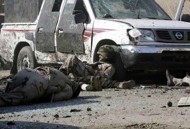 Iraqi Army soldiers lay dead and wounded moments after a suicide attack on a celebration marking Army Day in the Karradah neighborhood of central Baghdad, on January 6, 2008. Two Iraqi army soldiers threw themselves atop a suicide bomber, but the attacker was able to detonate an explosives vest, killing the two soldiers and another nine people. The civilian from the previous photo was among those killed, his foot visible at right. (Photo by Hadi Mizban/AP Photo/The Atlantic)