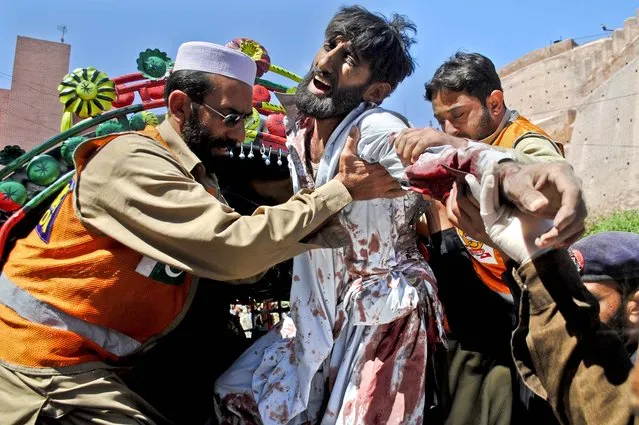 Volunteers help an injured man arriving at a local hospital after a car bomb exploded in a refugee camp outside of  Peshawar, Pakistan, killing and wounding dozens of people, on March 21, 2013. (Photo by Sohail Iqbal/Associated Press)