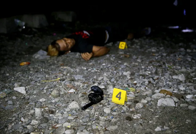 A pistol is lies near the body of a drug suspect who was killed with two others in an alleged “buy-bust” operation before dawn on Friday, September 30, 2016, in Caloocan city, north of Manila, Philippines, in the continuing “War on Drugs” campaign of President Rodrigo Duterte. Duterte said he would be “happy to slaughter” 3 million addicts. (Photo by Bullit Marquez/AP Photo)