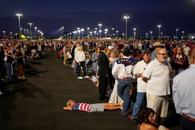 A boy, wearing an American flag-themed shirt, lies on the ground as people arrive, ahead of the morning sunlight, to attend a memorial service for slain conservative commentator Charlie Kirk at State Farm Stadium, in Glendale, Arizona, U.S., September 21, 2025. (Photo by Cheney Orr/Reuters)
