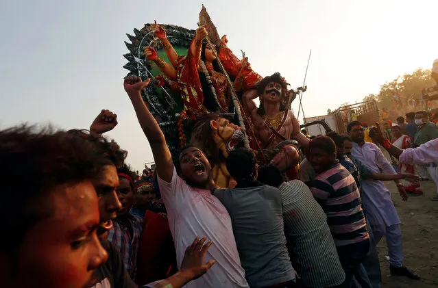 Devotees shout religious slogans as they carry an idol of the Hindu goddess Durga to immerse in the Yamuna River on the last day of the Durga Puja festival in New Delhi, India October 11, 2016. (Photo by Adnan Abidi/Reuters)