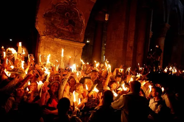 Worshipers light candles lit from a flame that emerged from the tomb believed to be of Jesus Christ as they take part in the ceremony of the holy fire at the Church of the Holy Sepulcher in Jerusalem, Israel, on May 4, 2013. (Photo by Lior Mizrahi/Getty Images)