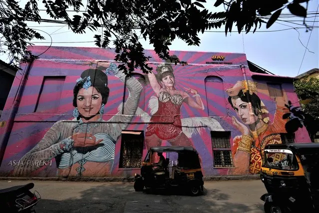 Autorickshaws drive past a mural of a Bollywood actress at Bandra in Mumbai, India, Friday, March 17, 2023. India will soon eclipse China to become the world's most populous country, and its economy is among the fastest-growing. But the number of Indian women in the workforce, already among the 20 lowest in the world, has been shrinking for decades. (Photo by Rajanish Kakade/AP Photo)