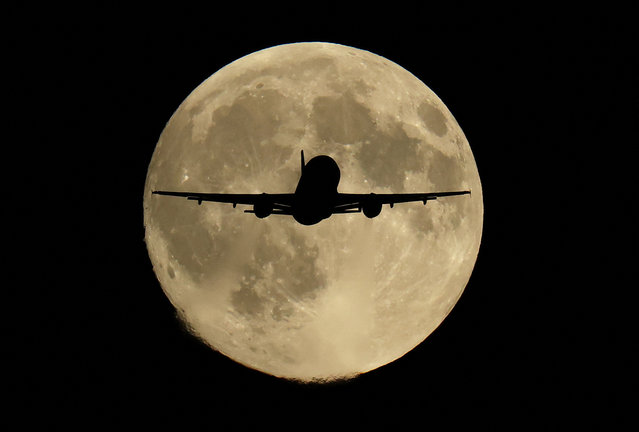 A passenger plane passes in front of the first supermoon of the year, known as the Harvest Moon, as it flies above London, Britain, on October 6, 2025. (Photo by Toby Melville/Reuters)