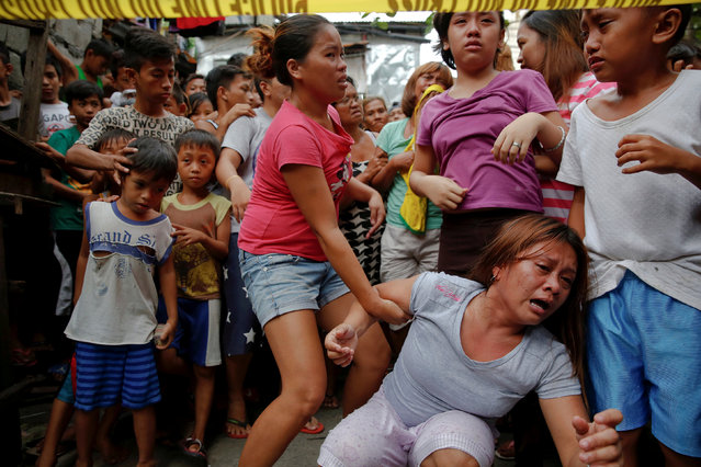 Janeth Mejos reacts as the body of her father Paquito Mejos is taken out of their home shortly after he was killed in a police operation in Manila, Philippines October 14, 2016. (Photo by Damir Sagolj/Reuters)