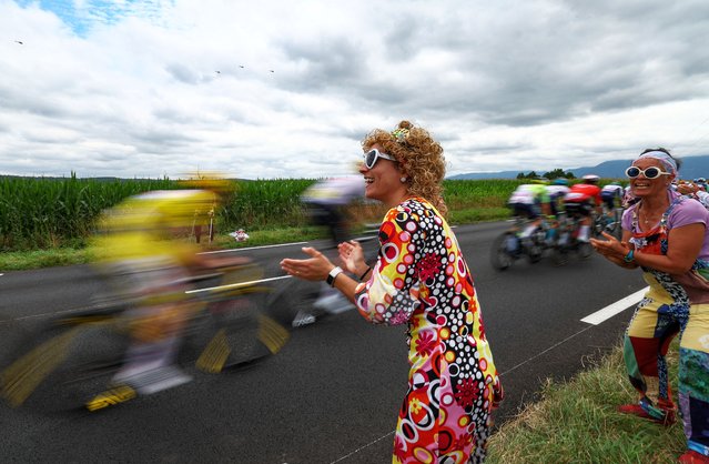 Spectators in colourful attire cheer as the pack of riders (peloton) cycles by during the 14th stage of the 111th edition of the Tour de France cycling race, 151,9 km between Pau and Saint-Lary-Soulan Pla d'Adet, in the Pyrenees mountains in southwestern France, on July 13, 2024. (Photo by Anne-Christine Poujoulat/AFP Photo)