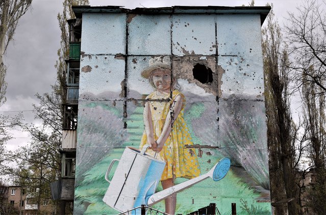 A mural is seen on a heavily damaged residential building in the frontline town of Avdiivka, Donetsk region on April 25, 2023, amid the Russian invasion of Ukraine. (Photo by Anatolii Stepanov/AFP Photo)