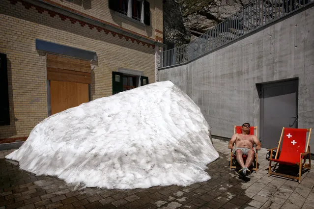 A man enjoys the warm sun next to a pile of snow on the Pilatus mountain, Switzerland, on June 18, 2013. Weather forecasts predict hot temperatures to continue in Switzerland. (Photo by Alexandra Wey/European Pressphoto Agency)