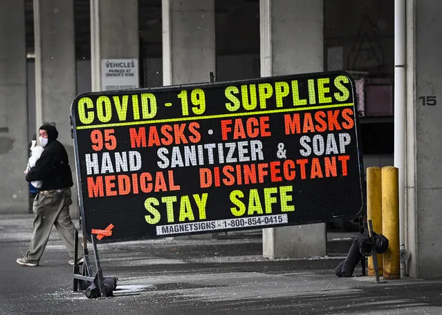 A man walks past a COVID-19 retail supplies sign during the COVID-19 pandemic in Toronto, Friday, February 5, 2021. (Photo by Nathan Denette/The Canadian Press via AP Photo)