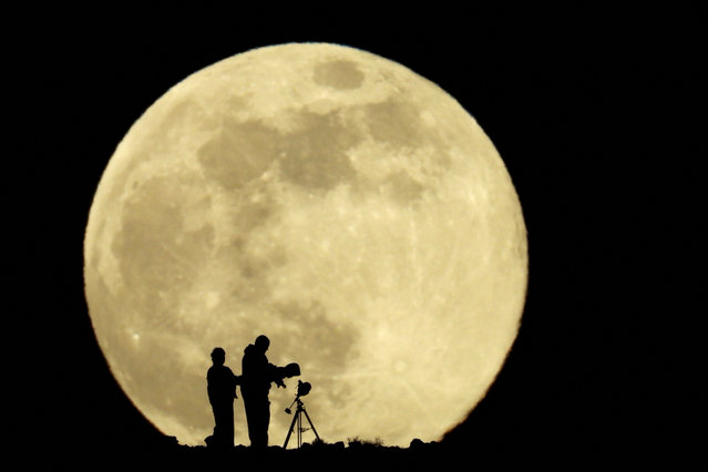 A couple and their daughter use a telescope to observe the last supermoon of 2025, known as the Cold Moon, in Aguimes, on the island of Gran Canaria, Spain, on December 4, 2025. (Photo by Borja Suarez/Reuters)