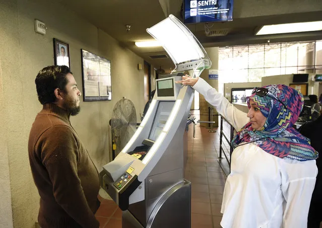 Contractor Sabira Dewji, right, helps a pedestrian crossing from Mexico into the United States at the Otay Mesa Port of Entry have his facial features and eyes scanned at a biometric kiosk Thursday, December 10, 2015, in San Diego. On Thursday, U.S. Customs and Border Protection began capturing facial and eye scans of foreigners entering the country at San Diego's Otay Mesa port of entry on foot. (Photo by Denis Poroy/AP Photo)