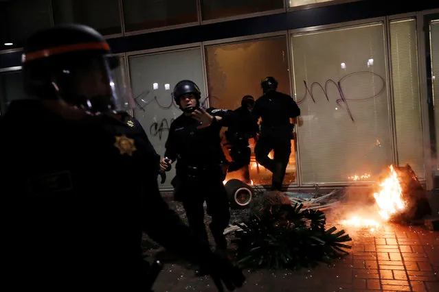 Police officers work to control the scene of an office set aflame by demonstrators during a demonstration in Oakland, California, U.S. following the election of Donald Trump as President of the United States November 9, 2016. (Photo by Stephen Lam/Reuters)