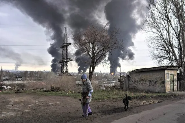 A woman walks as smoke rises in the air in the background after shelling in Odesa, Ukraine, Sunday, April 3, 2022. (Photo by Petros Giannakouris/AP Photo)