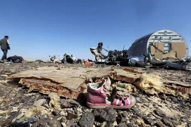 A child's shoe is seen in front of debris from a Russian airliner which crashed in the Hassana area in Arish city, Egypt, November 1, 2015. (Photo by Mohamed Abd El Ghany/Reuters)