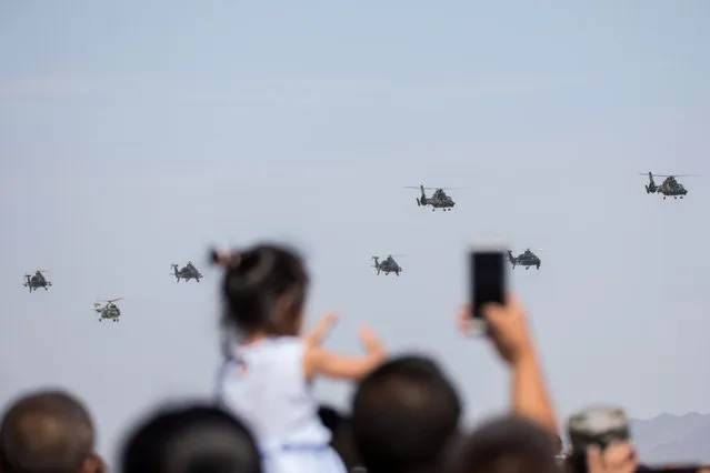 Spectators take photos as helicopters perform during the opening ceremony of three games hosted by Chinese People's Liberation Army (PLA), part of International Army Games 2018 in Korla, Xinjiang Uighur Autonomous Region, China on July 30, 2018. (Photo by Reuters/China Stringer Network)