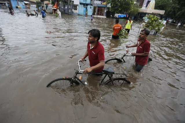 Indian men push their cycles past floodwaters after heavy rainfall in Ahmadabad, India, Friday, August 17, 2018. India receives its annual rainfall from June-October. (Photo by Ajit Solanki/AP Photo)