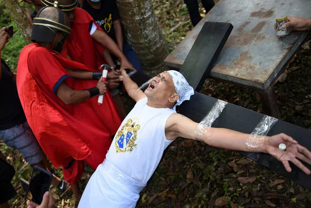 Filipino penitent Greg Meer reacts as he is nailed on a cross during a reenactment of Jesus Christ's crucifixion, in Santo Tomas, Batangas province, Philippines, March 30, 2021. (Photo by Lisa Marie David/Reuters)