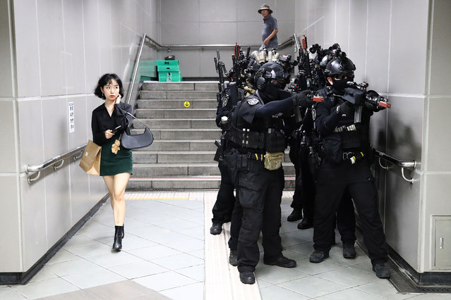 A woman walks past as South Korean soldiers participate in an anti-chemical and anti-terror exercise as part of the 2023 Ulchi Freedom Shield (UFS) at subway station on August 22, 2023 in Seoul, South Korea. The 11-day exercise, which features drills including the handling of chemical and biological attacks, is a regular joint exercise between U.S. and South Korean troops. The exercise serves as a platform for the South Korean government to prepare for potential emergencies on the Korean Peninsula, with some 580,000 officials from about 4,000 city, county and ward governments, public institutions and others across the nation participating. (Photo by Chung Sung-Jun/Getty Images)