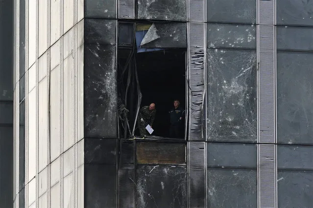 People inspect the damage sustained to a building of the Moscow International Business Center (Moskva City) following a drone attack in Moscow on August 23, 2023. A Ukrainian drone attack on Moscow damaged a building in a central business district, authorities said on August 23, in the sixth straight night of aerial attacks on Russia's capital region. (Photo by Natalia Kolesnikova/AFP Photo)